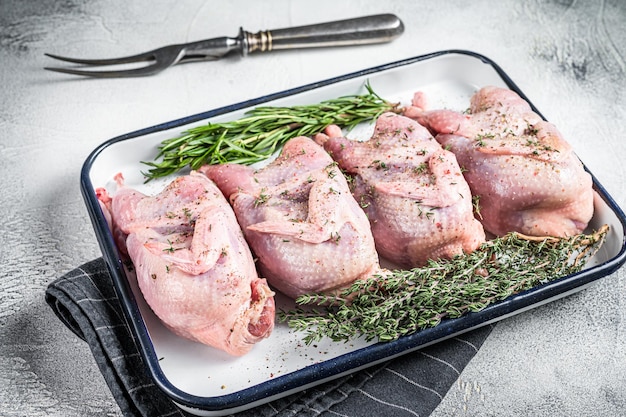 Viande de caille crue avec épices ail et herbes prêtes à cuire dans un plat allant au four Fond blanc Vue de dessus