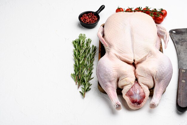 Photo viande de canard entière crue aux herbes sur fond de table en pierre blanche avec espace de copie pour le texte