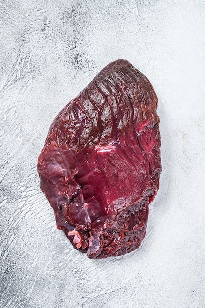 Viande de cerf cru de chevreuil sur une table. Table blanche. Vue de dessus.