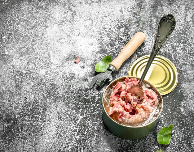 La viande en conserve dans une boîte de conserve sur une table rustique.