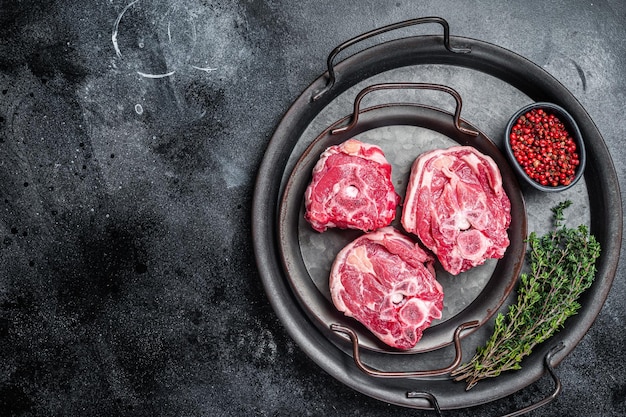 Viande de cou d'agneau crue avec os sur un plateau en acier Fond noir Vue de dessus Espace de copie