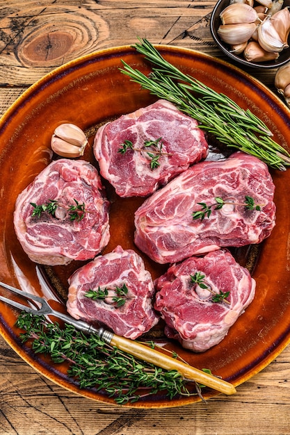 Viande de cou d'agneau de mouton sur une assiette rustique avec du thym et du romarin.