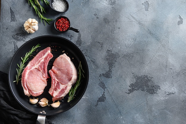 Viande crue aux herbes et épices sur ardoise noire sur fond gris