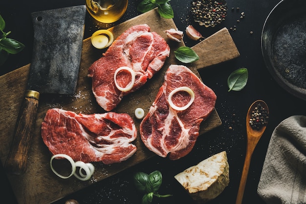 Viande crue à bord avec des épices et des herbes à bord sur une surface sombre