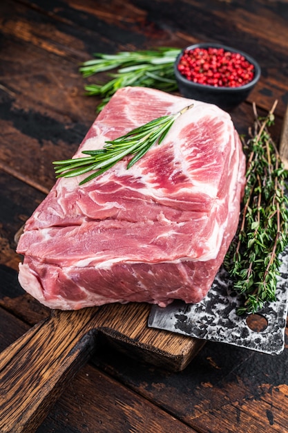 Viande crue de cou de porc pour les steaks hachés frais sur une planche à découper en bois avec couperet de boucher. Bois foncé