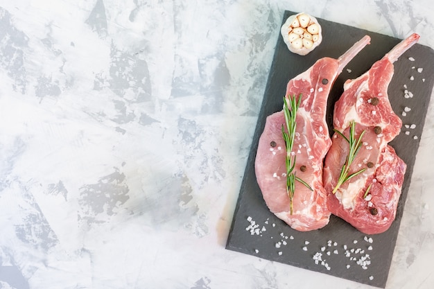 Viande Crue En Deux Morceaux Sur Une Planche à Découper Au Romarin