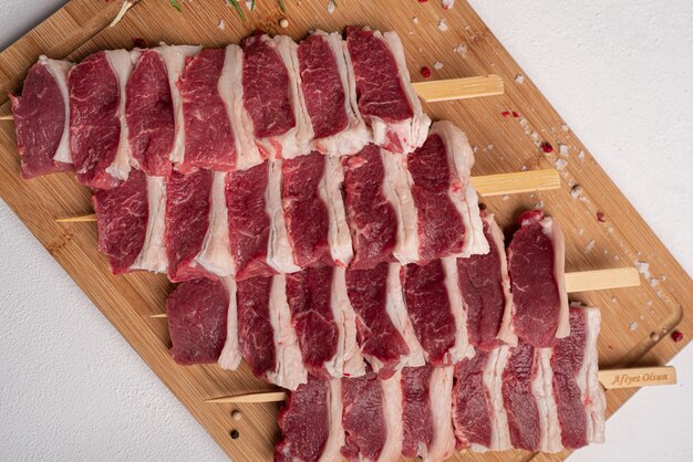 Viande crue sur fond blanc. Petits morceaux de viande crue sur des brochettes en bois