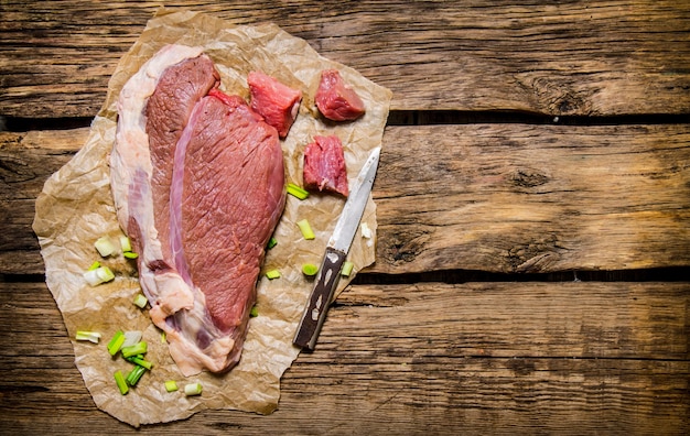 Viande crue fraîche avec un couteau de boucher. Sur fond de bois. Espace libre pour le texte. Vue de dessus