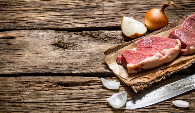 Viande crue fraîche avec un couteau de boucher et un oignon.