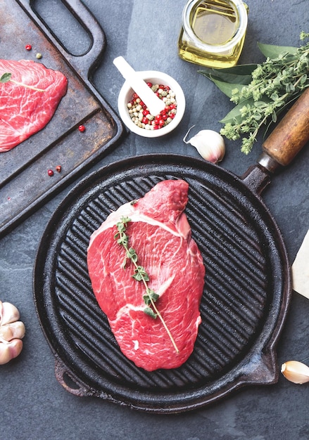 Viande crue fraîche Filet de boeuf et steaks de boeuf marbrés sur une poêle à griller et une planche à frire avec vue de dessus sur fond noir assaisonné