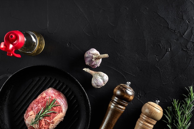 Viande crue fraîche Filet de boeuf et steaks de boeuf marbrés sur une poêle à griller et une planche à frire avec vue de dessus sur fond noir assaisonné