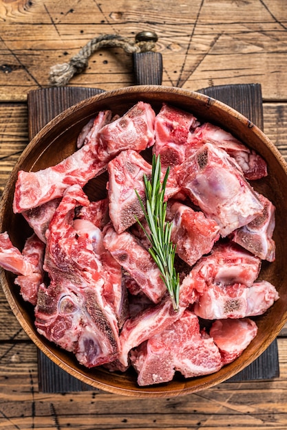 Viande crue fraîche sur l'os coupée en dés pour le goulasch dans une assiette en bois. table en bois. Vue de dessus.