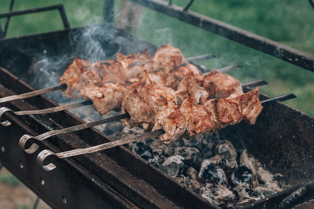 La viande crue grillée sur des brochettes est cuite sur un gril au charbon de bois, faisant cuire un barbecue à l'extérieur