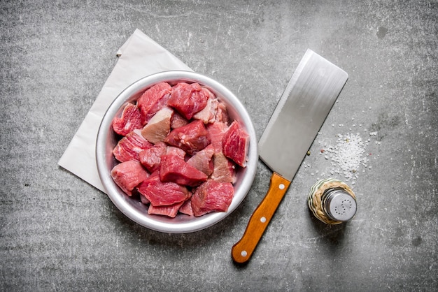 Photo viande crue hachée avec un couteau de boucher et sel sur la table en pierre