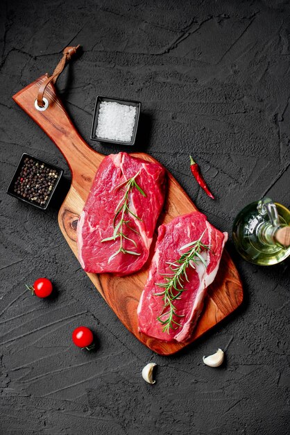 Viande crue sur une planche de bois avec des épices et des herbes.