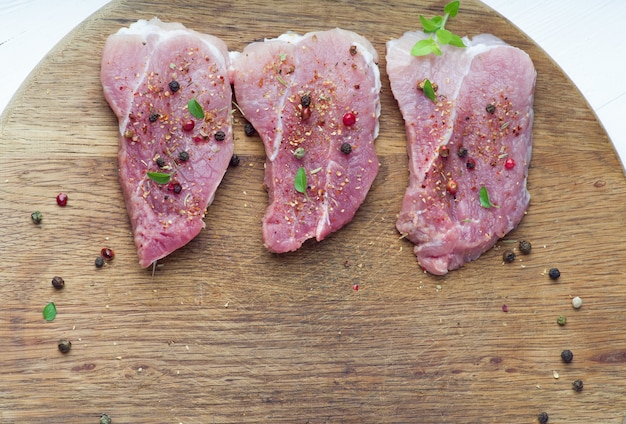 Viande crue sur une planche à découper en bois avec des épices