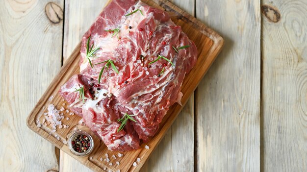 Viande crue sur une planche avec du sel et des épices. Cou de porc.