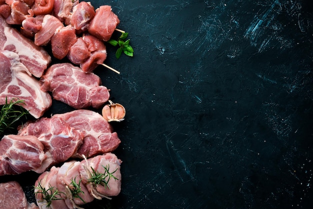 Viande crue pour barbecue Viande aux épices et herbes Sur fond de pierre noire Vue de dessus Espace de copie gratuit