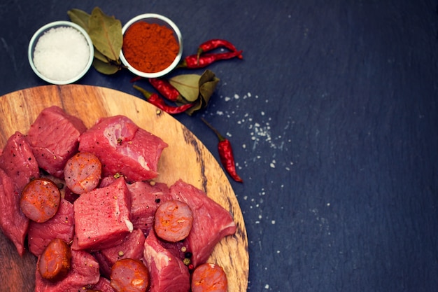 Viande crue avec saucisse fumée sur planche de bois