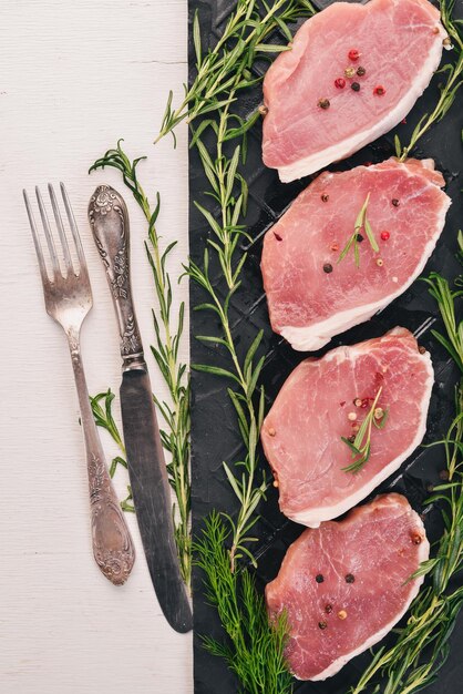 Viande crue Steak de boeuf au romarin et épices sur un fond en bois blanc Vue de dessus Espace libre pour le texte