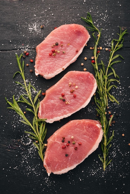 Viande crue Steak de boeuf au romarin et épices sur un fond en bois noir Vue de dessus Espace libre pour le texte