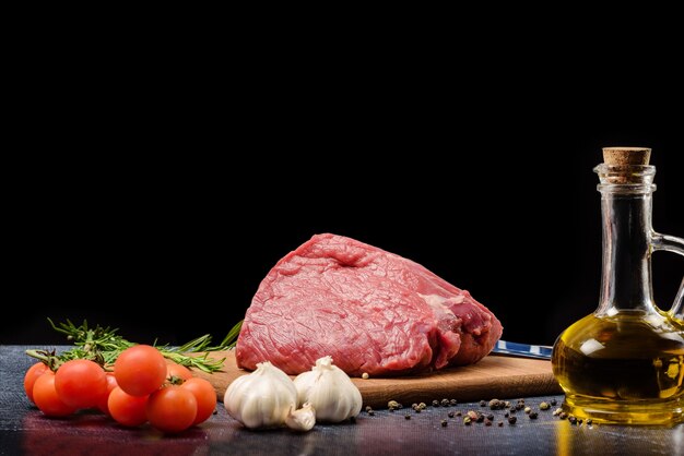 Viande crue sur une table avec des épices, isolée sur fond noir