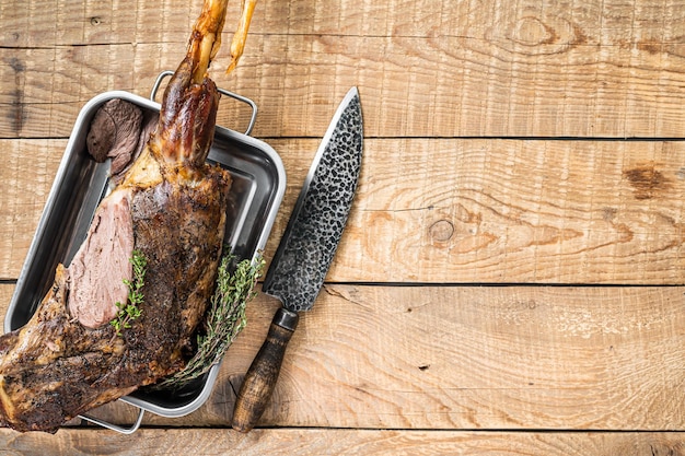 Viande de cuisse de chèvre entière rôtie au four avec du thym dans un plateau en acier Fond en bois Vue de dessus Espace de copie