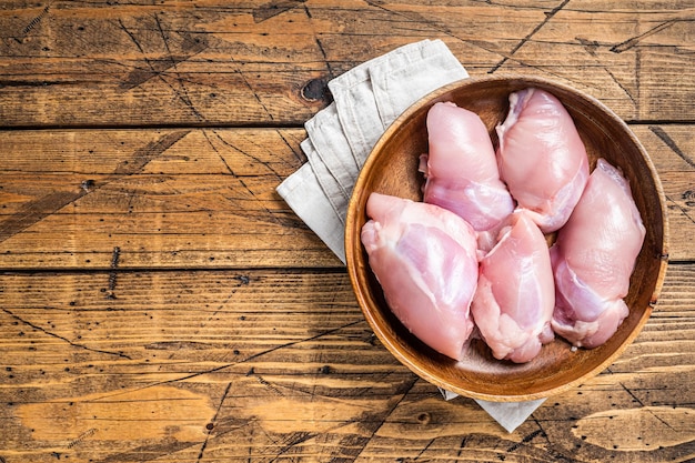 Viande de cuisse de poulet fraîche crue Filet désossé et sans peau dans une assiette en bois Fond en bois Vue de dessus Espace de copie