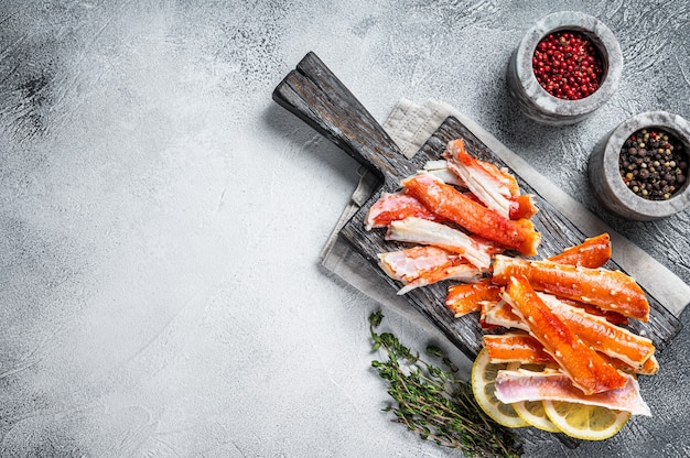 Viande cuite de pattes de crabe royal sur une planche de bois avec des herbes. Fond blanc. Vue de dessus. Espace de copie.