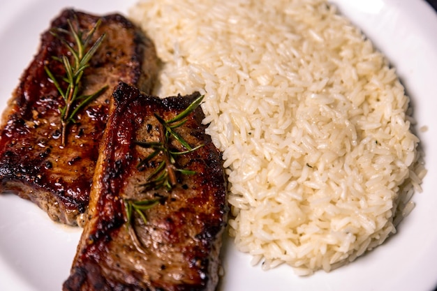 Une viande délicieuse avec de la viande de riz et du riz sur un plat blanc