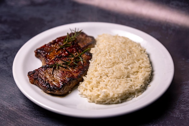 Une viande délicieuse avec de la viande de riz et du riz sur un plat blanc