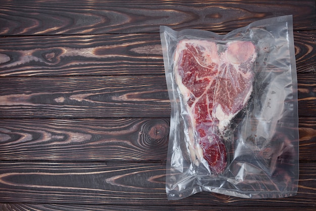 Viande emballée sous vide sur fond de bois ancien.