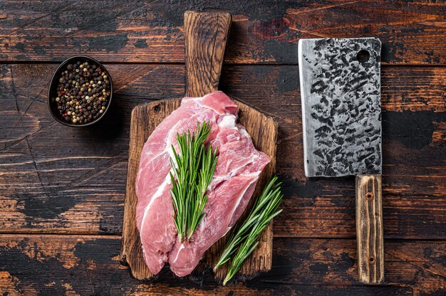 Viande d'épaule de porc crue fraîche coupée avec des ingrédients et des épices sur fond de cuisine. Fond en bois sombre. Vue de dessus.