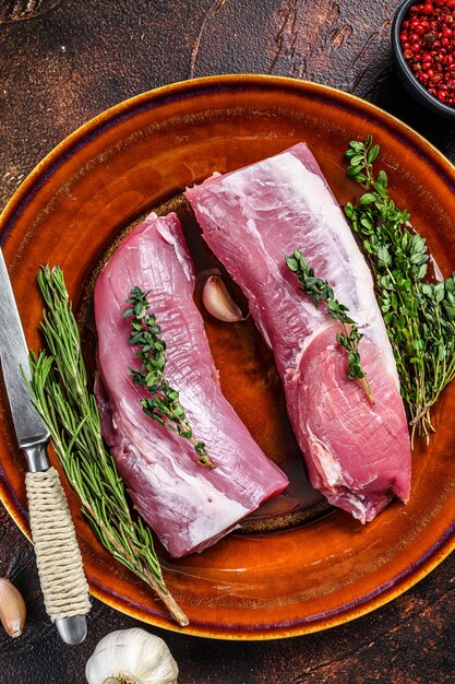 Viande de filet de porc frais au romarin et au thym. Fond sombre. Vue de dessus.