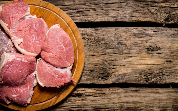 Viande fraîche crue sur une planche à découper. Sur table en bois.