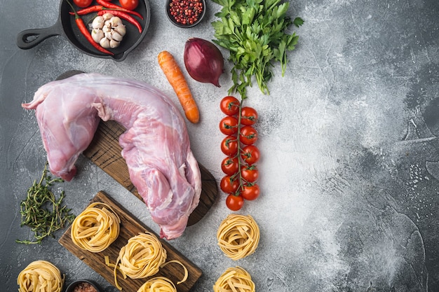 Viande fraîche. Ensemble de tagliatelles de ragoût de lapin entier prêt à cuire, sur une table en pierre grise, vue de dessus à plat