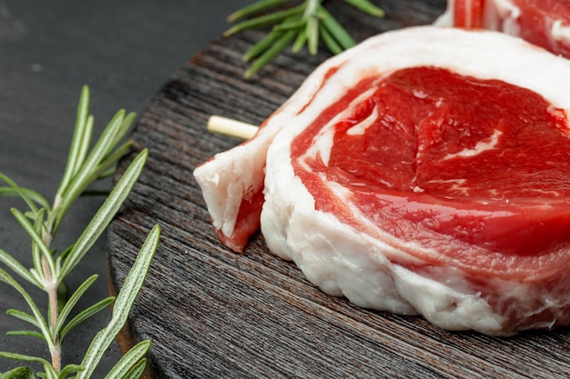 Viande fraîche avec des ingrédients pour la cuisson sur fond sombre