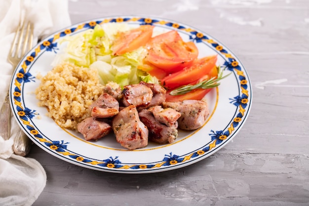 Viande frite au quinoa et salade fraîche sur plaque sur fond en céramique