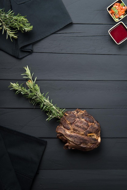 Viande frite avec des verts, de la sauce et de la sauce sur un fond en bois noir