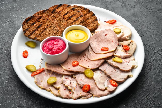 Viande fumée tranchée et salami avec sauce sur une assiette blanche Vue de dessus