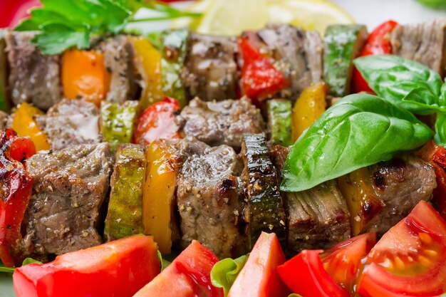 Viande grillée en brochettes avec légumes sur feuilles de salade