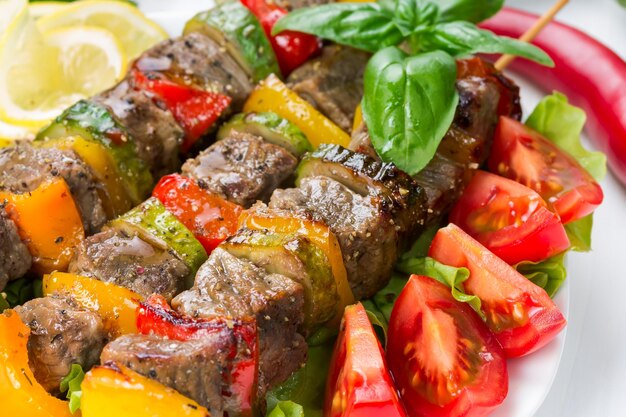 Viande grillée en brochettes avec légumes sur feuilles de salade