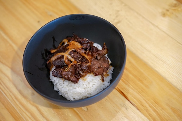 Viande grillée sur le riz japonais avec fond de table en bois.