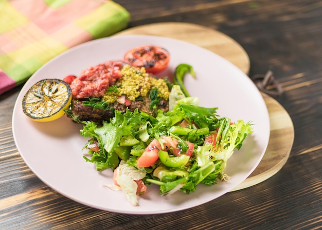 Viande grillée et salade de légumes frais d'un plat sur un fond en bois