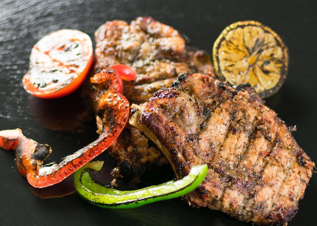 Viande grillée servie avec des épices de légumes sur une plaque d'ardoise