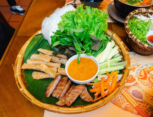 Viande grillée vietnamienne ou enveloppe de boulettes de viande avec légumes et sauce sucrée (Nham Neung) sur table, cuisine locale
