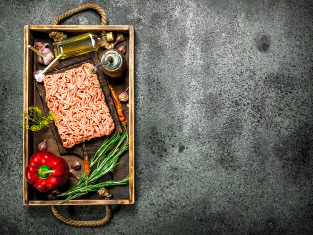 Viande hachée de boeuf aux épices et herbes sur un vieux plateau.