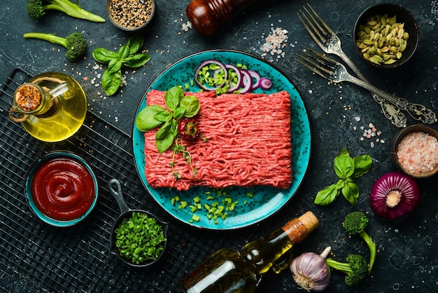 Viande hachée de boeuf hachée crue avec des herbes et des épices sur une assiette Vue de dessus Sur un fond de pierre