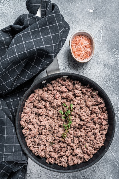 Viande hachée de boeuf et de porc hachée frite dans une poêle avec des herbes