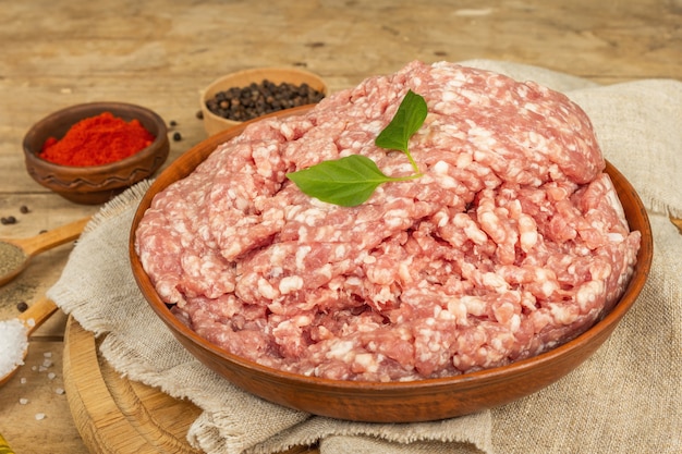 Viande hachée crue. Porc haché aux épices, huile de cuisson. Vieille table en bois, gros plan